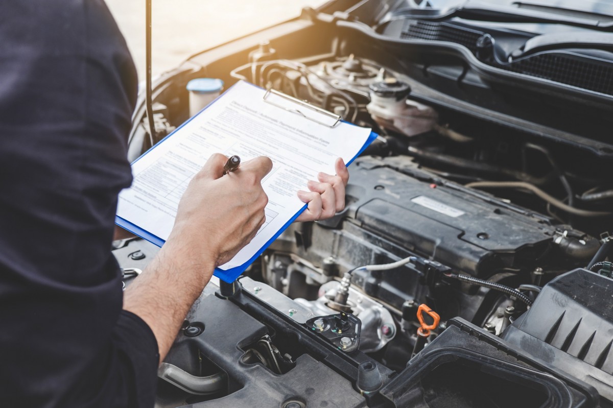 Mechanic holding checklist while checking on vehicle repairs